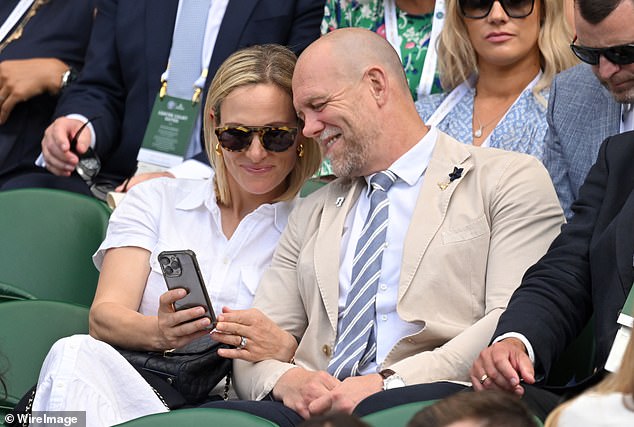 Zara and Mike smile as they look at her phone at Wimbledon in 2022