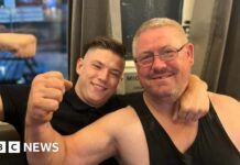 Kane Forder with his dad David both wearing black and with an arm raised in a flexing position