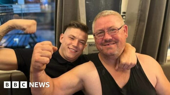 Kane Forder with his dad David both wearing black and with an arm raised in a flexing position