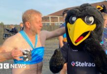 A man with a beer dressed as Princess Jasmine larking about with a person dressed as a giant black bird