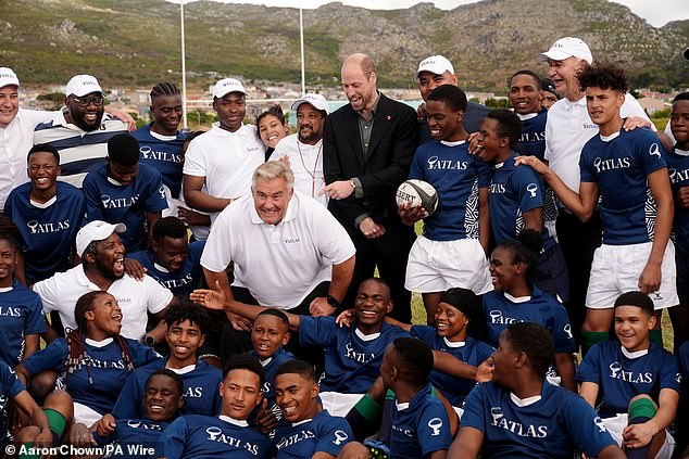 The Prince of Wales poses for a photograph with former England rugby player Jason Leonard and local school children after a session at Ocean View Secondary School in Cape Town today