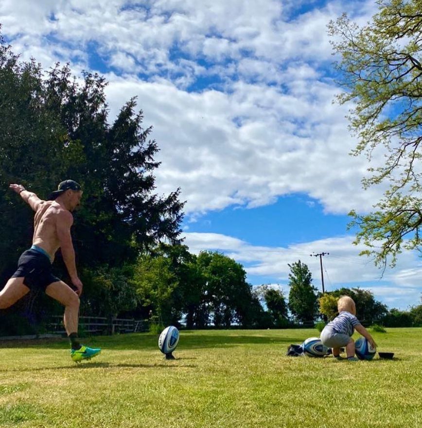 Owen Farrell kicking a rugby ball next to his son