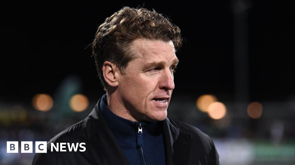 Mullin looking to the side, he has brown hair and is wearing a navy blue zip-up and a black jacket.
