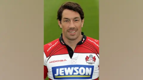 PA A head and shoulders shot of Tom Voyce in a Gloucester rugby kit. It is a red and white hooped shirt with the logo of the company Jewson across the chest.