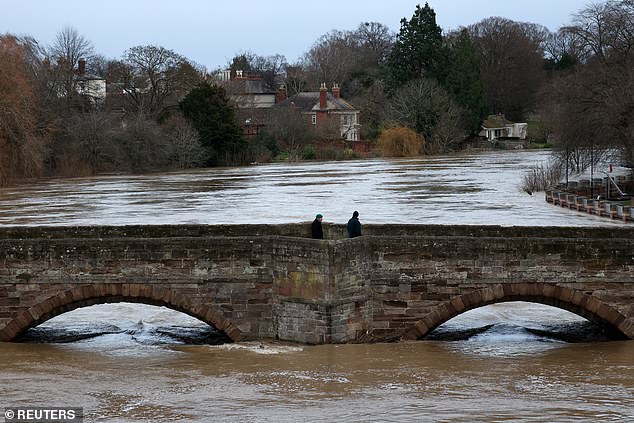 People cross a bridge over the River Wye after Storm Darragh hit the country, in Hereford on December 8