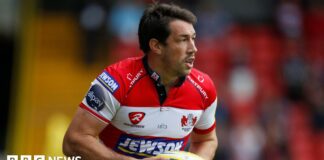 Tom Voyce playing for Gloucester, wearing a red and white shirt and carrying a ball.