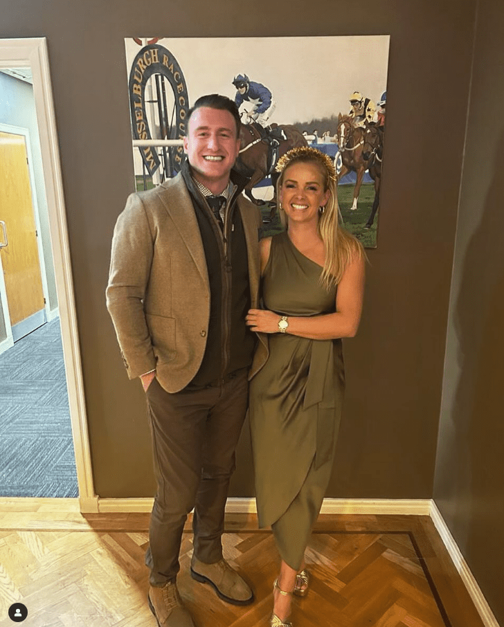 Couple posing for photo in front of a horse racing print.