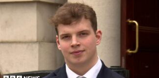 Gabe McConkey, young man with short brown hair, wearing black blazer, black tie and white shirt