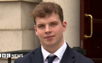 Gabe McConkey, young man with short brown hair, wearing black blazer, black tie and white shirt