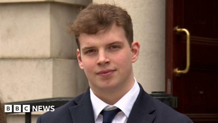 Gabe McConkey, young man with short brown hair, wearing black blazer, black tie and white shirt