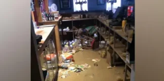 BBOB Rugby Club Flood waters in a bar with bottles and crisp packets floating in the brown water.