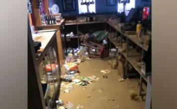BBOB Rugby Club Flood waters in a bar with bottles and crisp packets floating in the brown water.