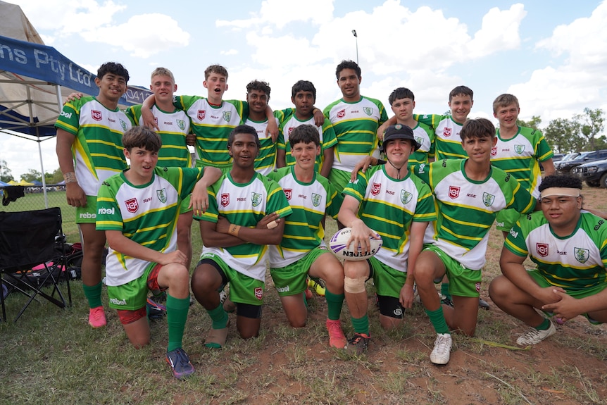 A junior rugby league team lined up on an oval for a photo.