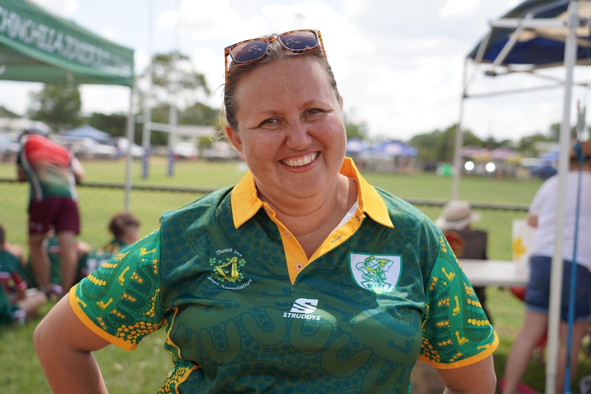 A smiling woman standing in front of a football ground.