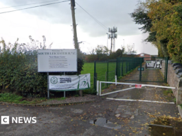 A gate road leading past a field to a rugby club