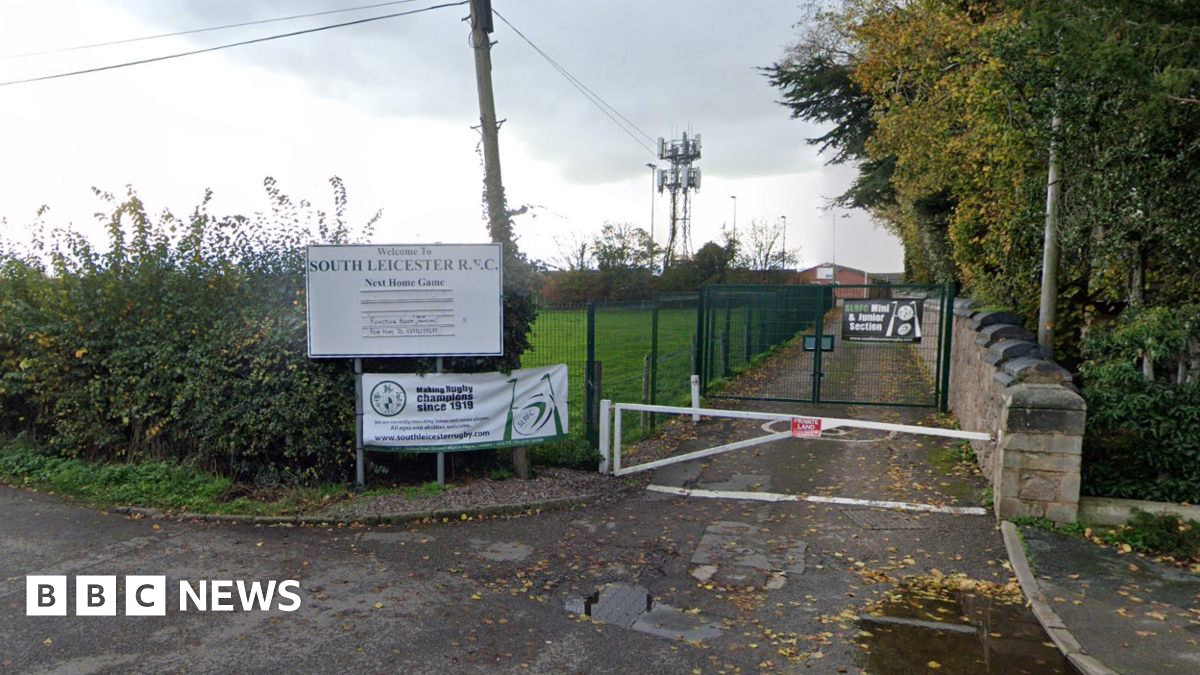 A gate road leading past a field to a rugby club