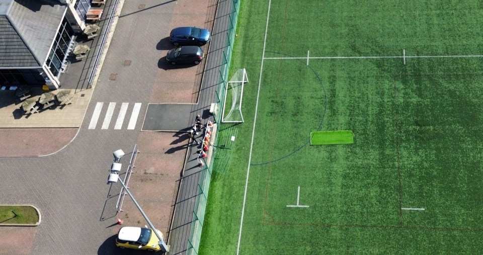 Aerial view of floral tributes and messages at a rugby club following a fatal accident.