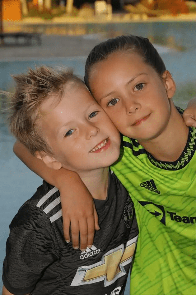 Two children hugging, wearing soccer jerseys.