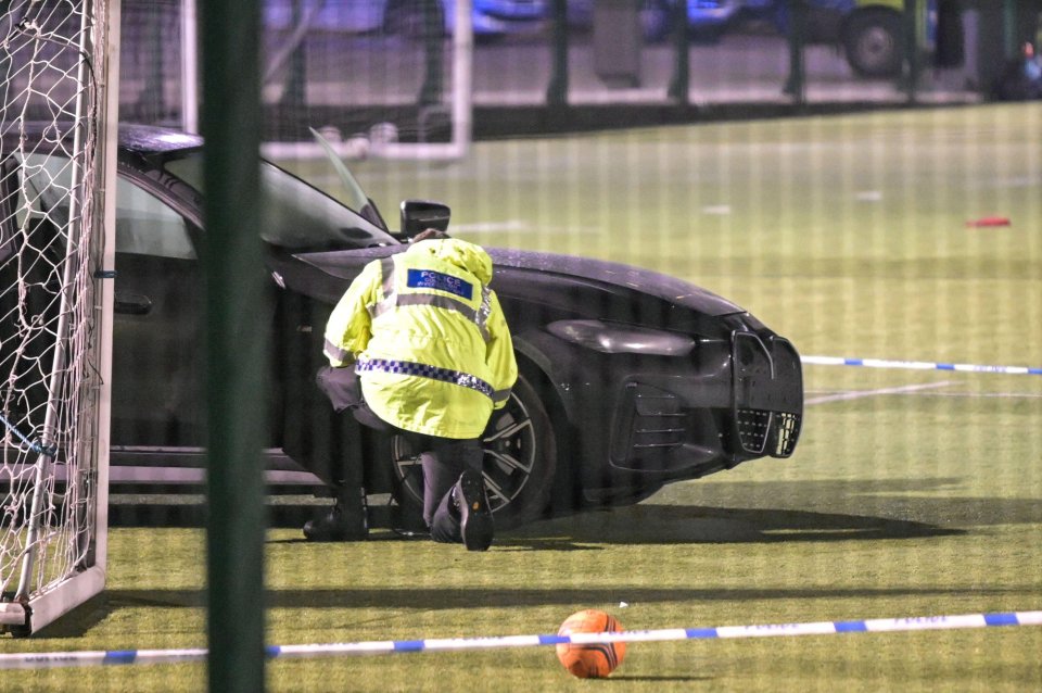 Police officer investigating a car crash on a soccer field.