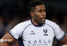 Viliame Mata stands with his hands on his hips