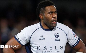 Viliame Mata stands with his hands on his hips
